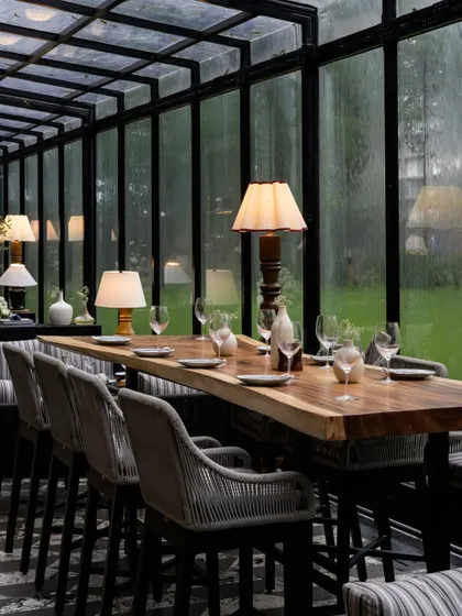 A long, live-edge wooden table provides a communal dining option at FIORI. This element, paired with comfortable high-chairs, adds a rustic yet sophisticated touch that complements the restaurant's nature-inspired theme.
