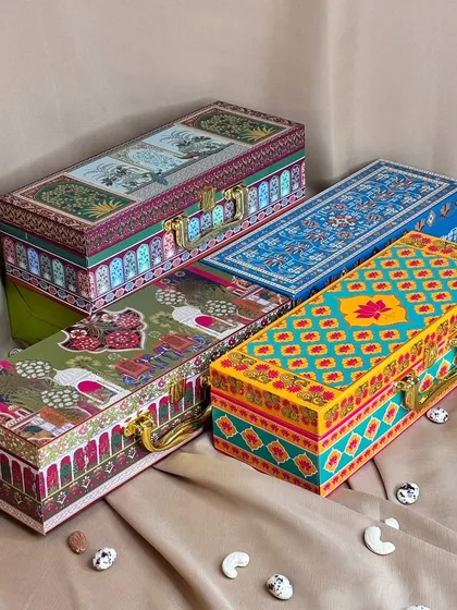 A collection of my rectangular dry fruit boxes, each with a unique, vibrant design and a sturdy handle. These are available with 3, 4, or 6 container options.