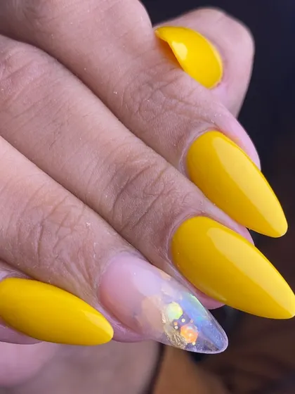 A sunny and bright design with a twist. This set features glossy yellow almond nails with one clear accent nail filled with iridescent glitter for a fun pop of sparkle.