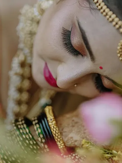 A delicate close-up shot of the bride, focusing on her flawless makeup, traditional bindi, and intricate hair accessories. I use soft focus and creative angles to create artistic and intimate bridal portraits.