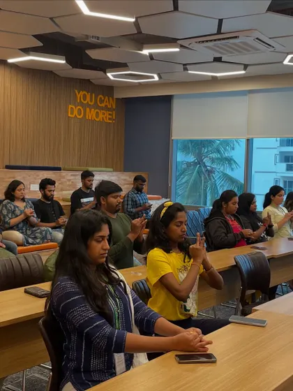 Employees at Ninjacart participating in a desk yoga session. They are practicing a mudra, a hand gesture that helps to focus the mind, even in a busy office environment.