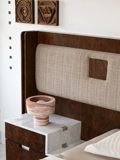 A close-up of the bedside table, showing the rich texture of the burlwood and the precise marble inlay work.
