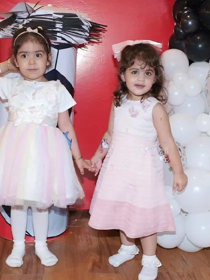 Two young friends hold hands at a football-themed birthday party.