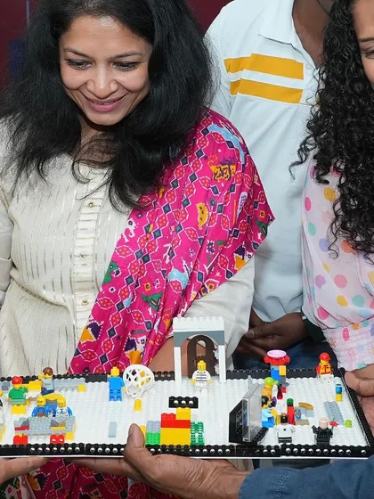 Adults get in on the fun too! Here, participants admire a detailed LEGO model of a bustling town square, complete with minifigures and intricate structures. LEGO is for everyone!