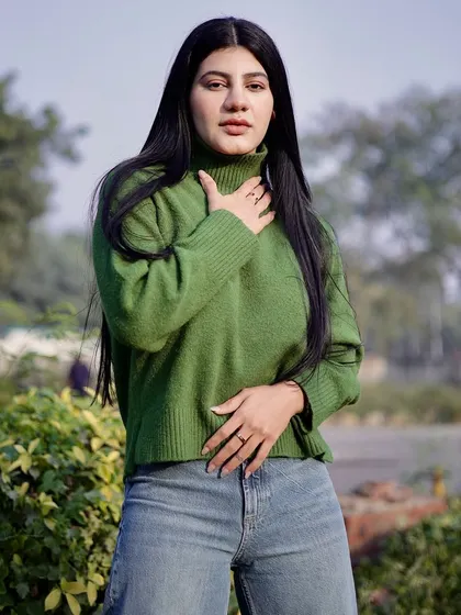 A medium shot of the model in a green sweater, with a focus on her expressive pose.