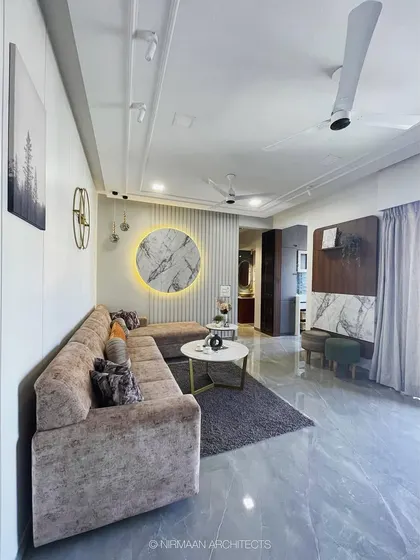 A wide view of the KVK Camellia living room, showcasing the L-shaped sofa and the backlit marble wall art. The design is clean, modern, and comfortable.