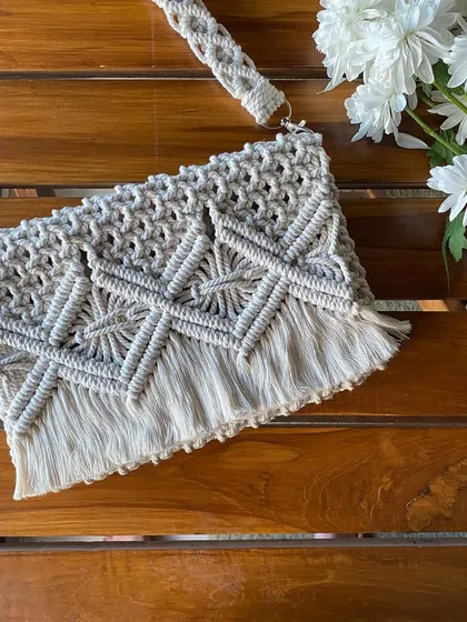 This shot highlights the texture and craftsmanship of the macrame bag, laid flat to show the full pattern and fringe detail.