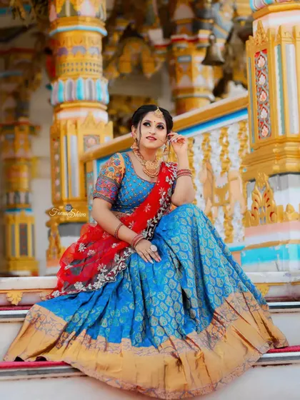 A moment of quiet elegance in our blue brocade half saree with a contrasting red embroidered dupatta.