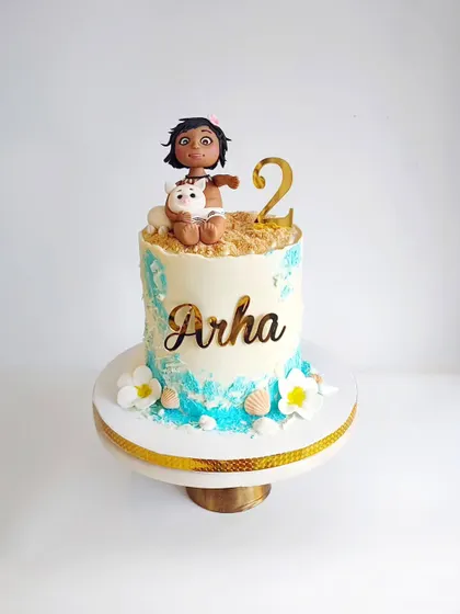 This Moana-inspired cake was a tropical dream for Arha's 2nd birthday. It features edible sand, ocean waves, and a handcrafted Moana topper, all on a delicious cake frosted with ganache.