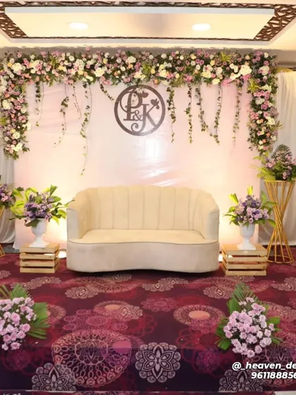 A full view of our personalized engagement stage, featuring the couple's monogram. The clean white backdrop is framed by a garland of pastel flowers and trailing ivy, creating a soft and romantic ambiance.