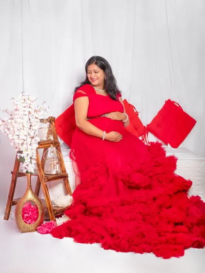 A serene indoor maternity shoot setup with our vibrant red ruffle gown. I provide props and a comfortable studio environment to capture these precious moments.