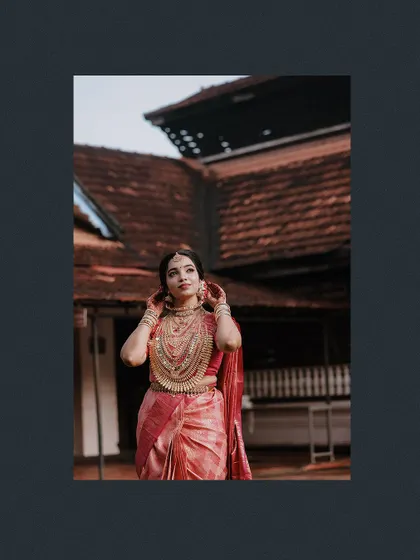 A stunning portrait of the bride against a traditional building, framed in a dark border.