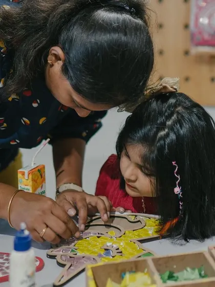 A mother helps her daughter with a mosaic project during a birthday party. These moments of collaboration and connection are what make art parties so special.