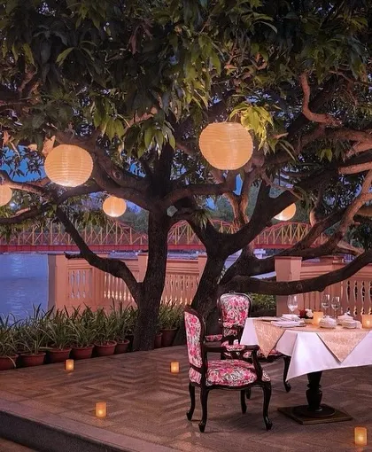 A romantic alfresco dining spot at IHCL Pilibhit-Haridwar, designed for intimate moments. The elegant, floral-patterned chair and soft lighting create a storybook setting by the pool.
