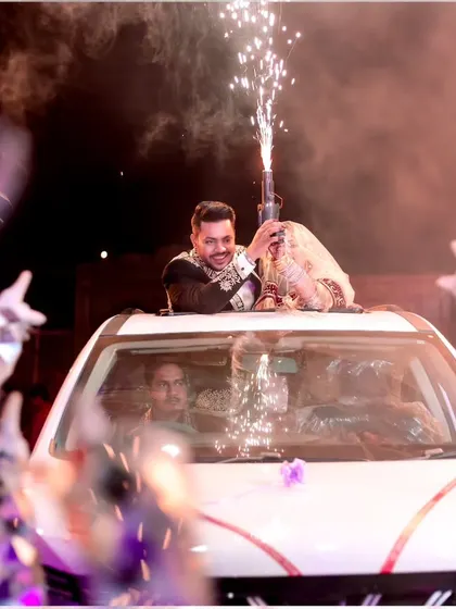 The grand exit! The newly married couple makes a celebratory departure through the car's sunroof, surrounded by friends and sparklers.