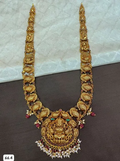 A detailed view of a 92.5 silver, gold-plated long haram. This piece features a large Lakshmi pendant and intricate carvings along the chain, perfect for a bridal look.