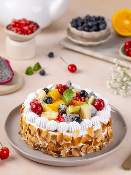 The whole fresh fruit cake, topped with a colorful assortment of fruits and toasted almonds.