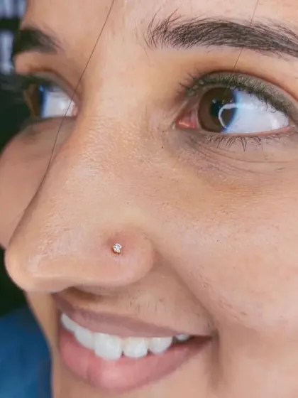 A close-up of a delicate, sparkling nose stud. This is a popular choice for a first nose piercing, and I ensure the placement is neat and flattering.