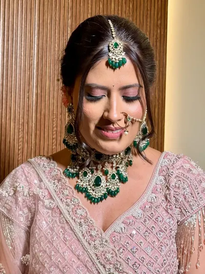 A close-up of the bride's soft, romantic makeup. The pink tones on her eyes and the emerald jewellery create a stunning contrast.