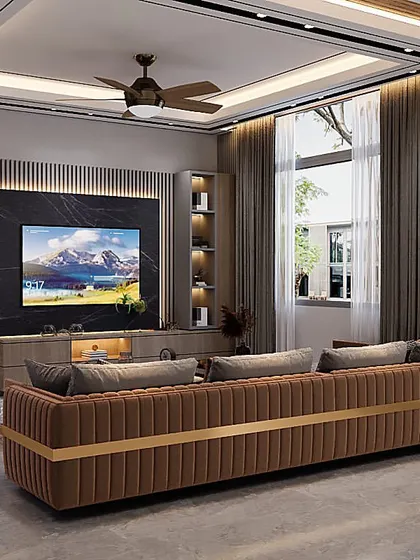 A completed living room project featuring a custom-made, channel-tufted brown sofa as the centerpiece. The media wall includes a black marble accent behind the TV and integrated shelving, all framed by elegant wood paneling.