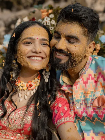 A heartwarming close-up of the couple, their faces smeared with haldi, sharing a genuine, happy smile.