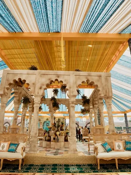 A frontal view of the magnificent carved stone pavilion, set under the striped blue and yellow canopy. This structure served as the stunning centerpiece of the 'Rang Mahal' celebration.