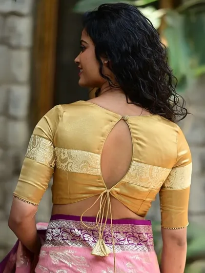 This golden blouse features a keyhole back with a tie-up tassel, combining a classic color with a modern design detail.