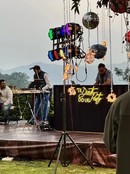The entertainment is key to a great party. This shot shows the DJ and live musician setup at an outdoor Sangeet, complete with professional lighting and a custom neon sign.