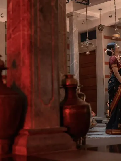 A wide shot capturing the couple within a traditional, ornate setting. The red tones of the pottery and the bride's sari create a warm and culturally rich atmosphere.
