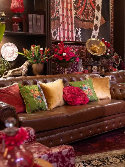 The heart of the lounge area is this classic brown leather Chesterfield, which I styled with a vibrant collection of velvet and embroidered cushions in jewel tones to add a pop of color and texture.