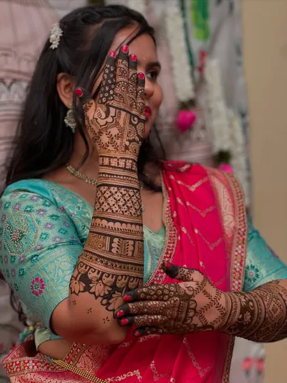 A side profile of a bride with her hands adorned in beautiful, intricate henna, demonstrating the elegance of the design.