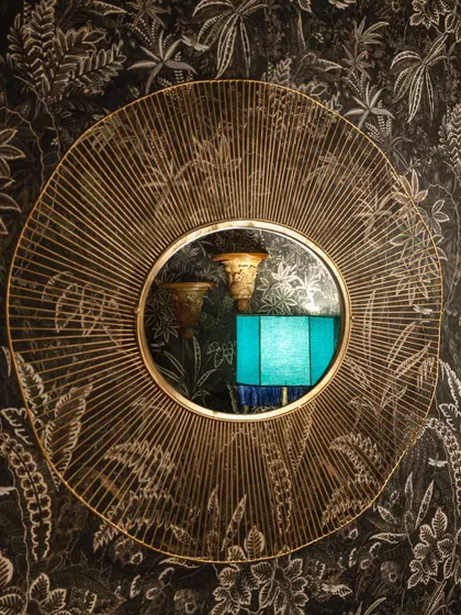 A decorative mirror reflects the unique textures and lighting of our interior, adding depth and a touch of artistry to the walls.