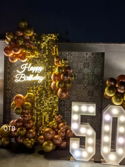 The 50th birthday setup at night, with the neon and marquee lights creating a warm and celebratory glow.
