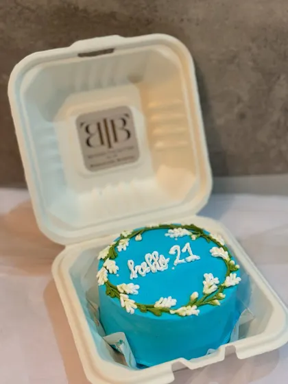 A "Hello 21" bento cake with a simple floral wreath design.