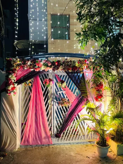 The entrance gate of the wedding house, beautifully decorated with pink and black drapes and lush floral arrangements.