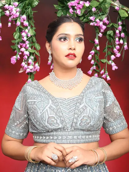 A portrait shot against a floral backdrop. The cool-toned makeup stands out beautifully against the red background.
