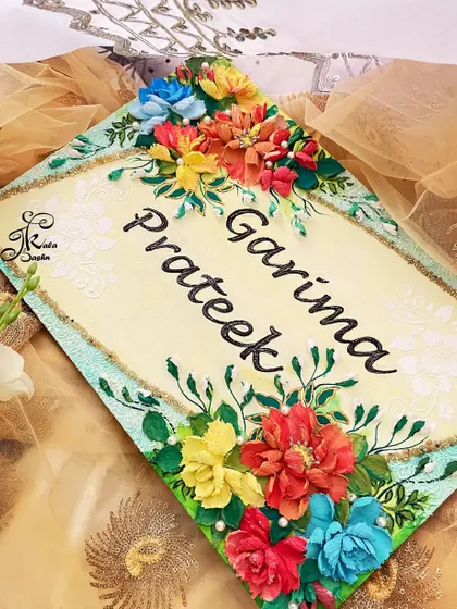 Another view of the "Garima & Prateek" nameboard, highlighting the pearl details and the delicate white stenciling on the background that adds another layer of texture.
