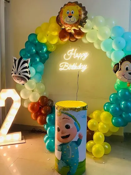 A Cocomelon and jungle animal themed birthday party. The setup includes a balloon ring, animal foil balloons, and a light-up number "2".