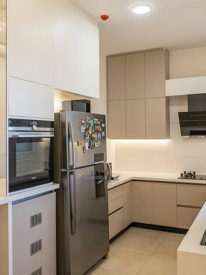 A view into the L-shaped kitchen area, showing the efficient layout with the refrigerator, oven tower, and cooktop all within easy reach.