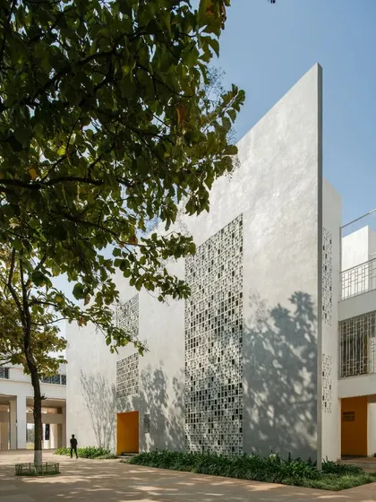A corner view of Vidyashilp Academy, where a solid wall meets a perforated one. The design plays with solid and void, creating a visually dynamic composition that is also highly functional in its response to the climate.