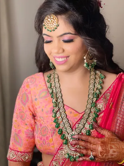 This happy client chose a long, multi-layered emerald green bead necklace with a matching maang tikka for her pre-wedding function.