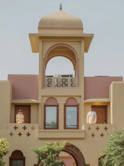A unique architectural shot of the groom and another family member on different balconies of the palace, taken during the Haldi preparations.