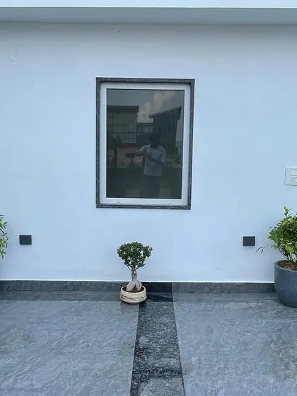 A minimalist entrance design featuring two ficus plants in grey pots flanking a small bonsai tree. This simple, symmetrical arrangement creates a calm and elegant welcome.