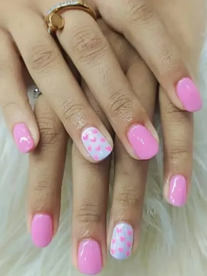 A sweet and simple design featuring a soft pink gel polish with accent nails that have a delicate pattern of tiny hearts. This is a perfect example of a subtle yet charming manicure.