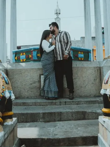 A wide shot of a couple posing at a historic monument in Mysore, framed by two elephant statues, creating a symmetrical and powerful pre-wedding image.