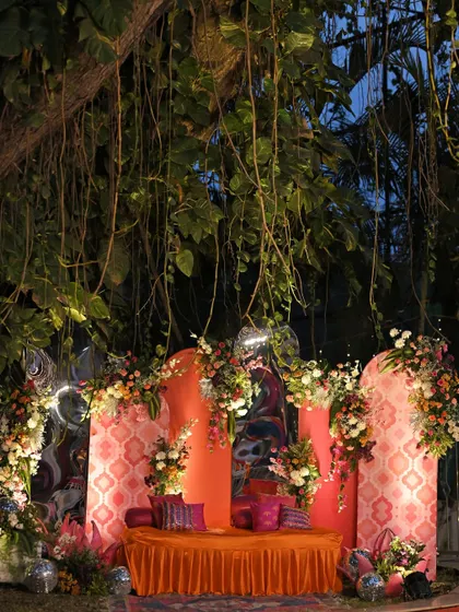 The Sangeet stage nestled under a large tree, with hanging vines and creative lighting. The colorful decor and relaxed seating create a festive, bohemian vibe for the celebration.