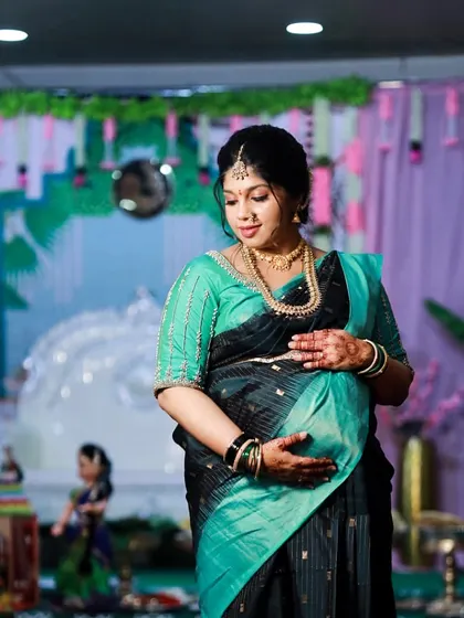 A glowing mom-to-be cradling her baby bump. The deep stain of her 100% natural henna adds to the beauty of this special moment.