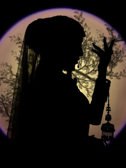 A dramatic silhouette of a bride against a lit backdrop. We use creative lighting techniques like this to produce artistic and mysterious portraits that stand out.