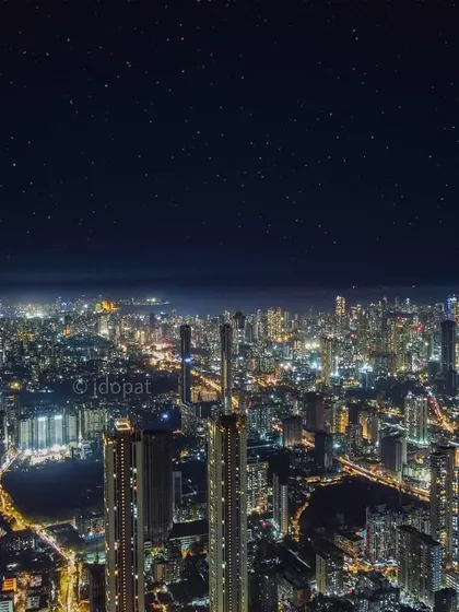 A wide aerial view of Mumbai at night, where the city's glow is so bright it rivals the starry sky above. This shot emphasizes the sheer scale and density of the urban landscape, a city that truly never sleeps.