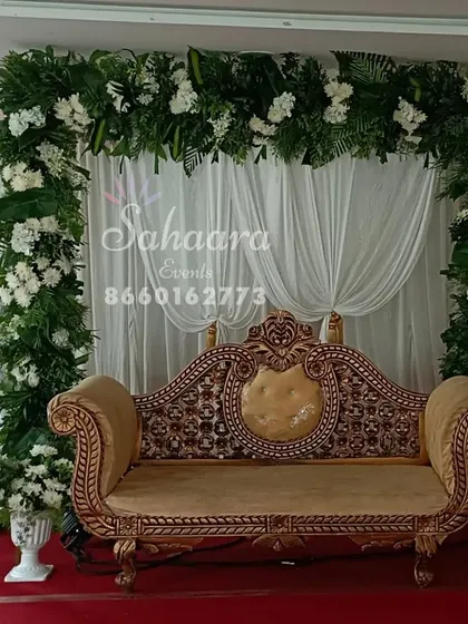 A lush green floral arch provides a beautiful frame for this engagement stage. The simple white drapery and classic gold-trimmed sofa create a look of natural elegance.